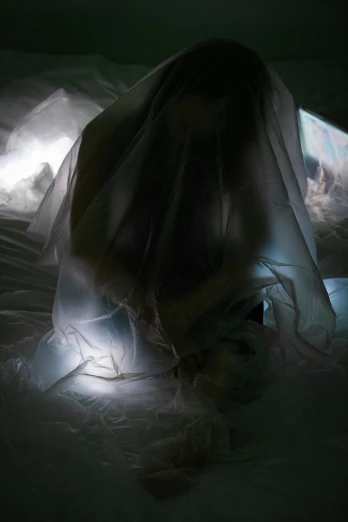 a woman sitting on top of a bed covered in a sheet, a hologram, inspired by Anna Füssli, unsplash, video art, in an icy cavern, white veil, dramatic soft shadow lighting, camera looking down into the maw