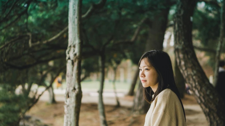 a woman standing in the middle of a forest, inspired by Jung Park, unsplash, korean girl, distant thoughtful look, at a park, 7 0 mm photo