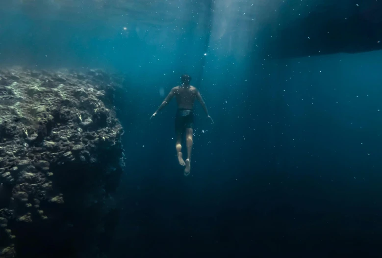a person swimming in a body of water, standing under the sea
