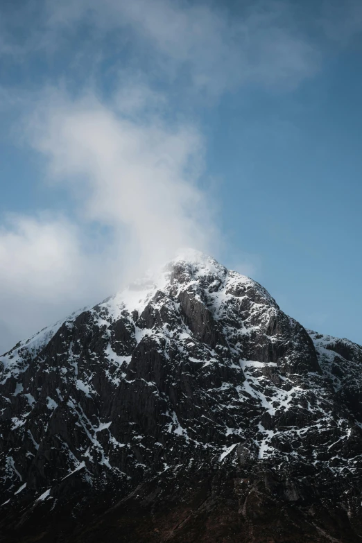 the snow capped mountain has clouds above it