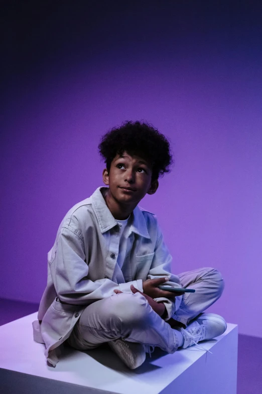 a man sitting on top of a white cube, an album cover, trending on unsplash, realism, portrait willow smith, ((purple)), finn wolfhard, dramatic lowkey studio lighting