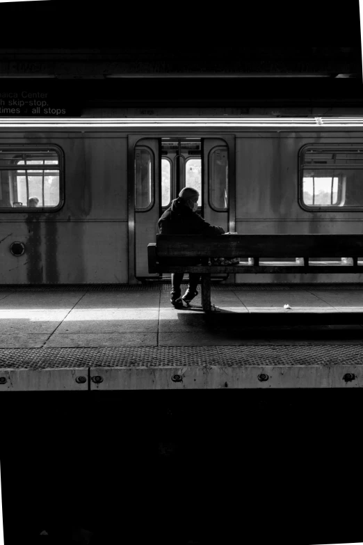 a person sitting on a bench next to a train