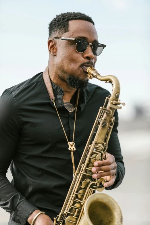 a man standing outside playing a saxophone