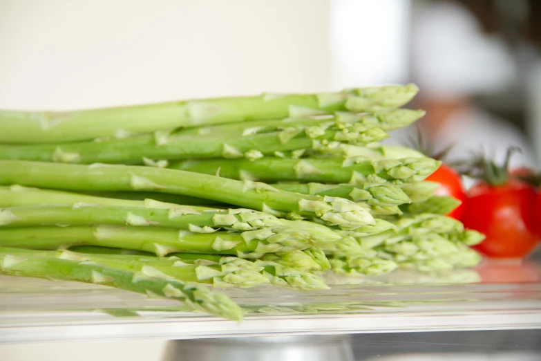 a stack of asparagus next to some tomatoes