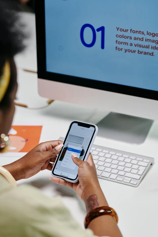 a woman sitting at a desk using a cell phone, trending on pexels, currency symbols printed, ui and ux, 9 9 designs, afro tech