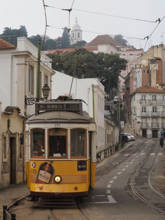 a yellow tram traveling on a winding street