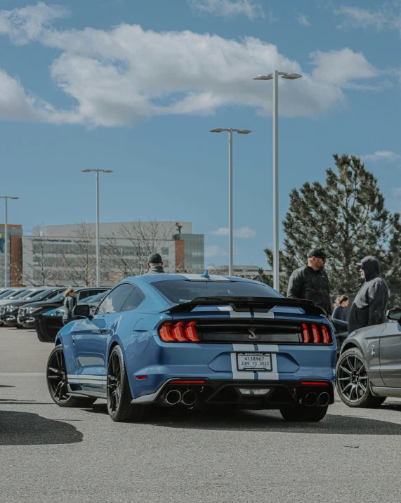 two cars parked in a parking lot with people around them