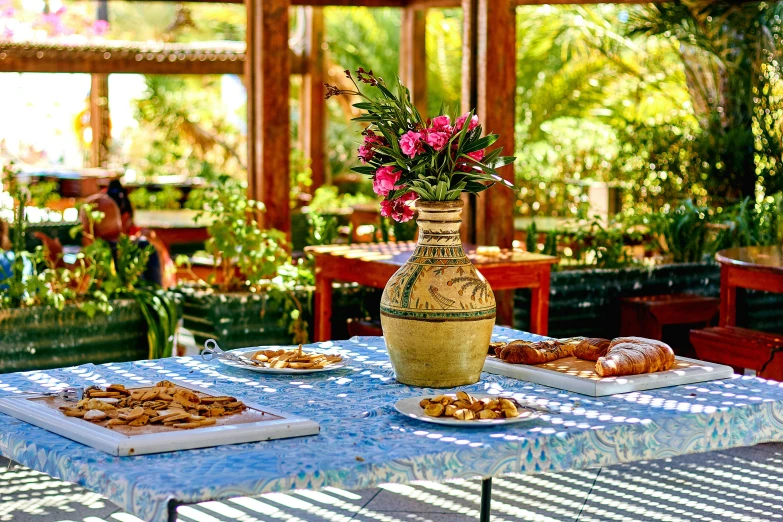 two plates of food on a table near a vase with flowers in it