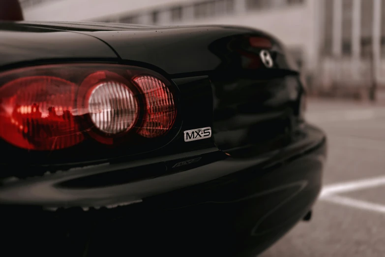 the back end of a black car parked in a lot