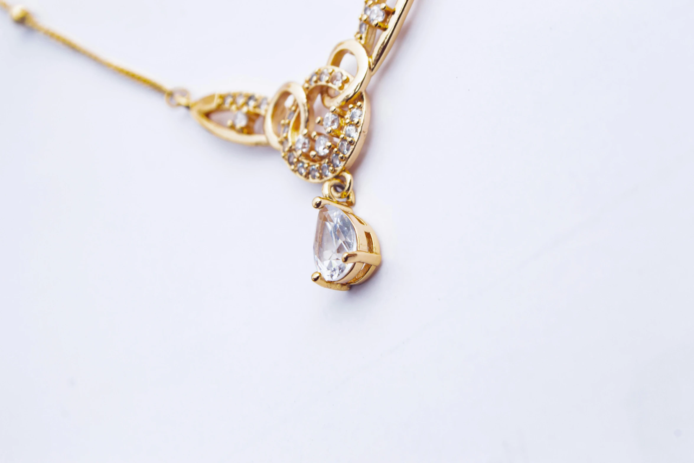 a close up of a necklace on a white surface, by Simon Gaon, trending on pexels, shiny golden, white background : 3, shot on sony a 7, high angle shot