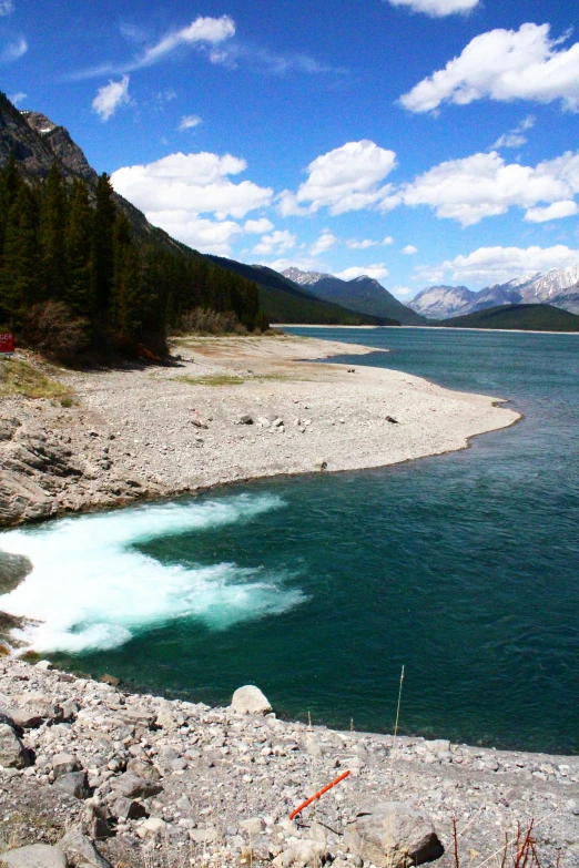 water on the rocks by a river with mountains