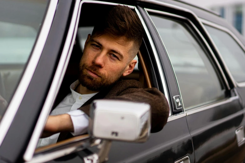 a man sitting in a car looking out the window, an album cover, by Daniel Seghers, pexels contest winner, short brown beard, john krasinski, professional model, square