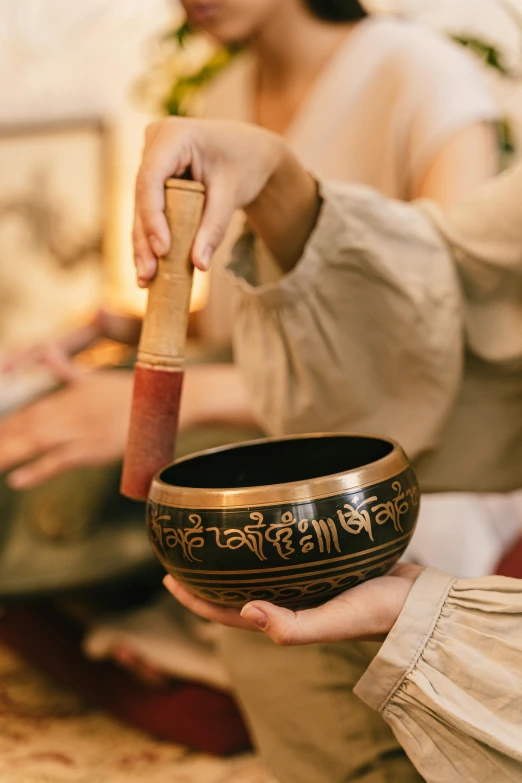 a person holding a singing bowl in their hand, thumbnail, gold inlay, prana, black