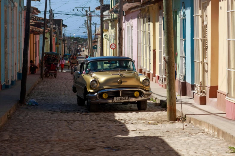 an old style car parked on a cobblestone street