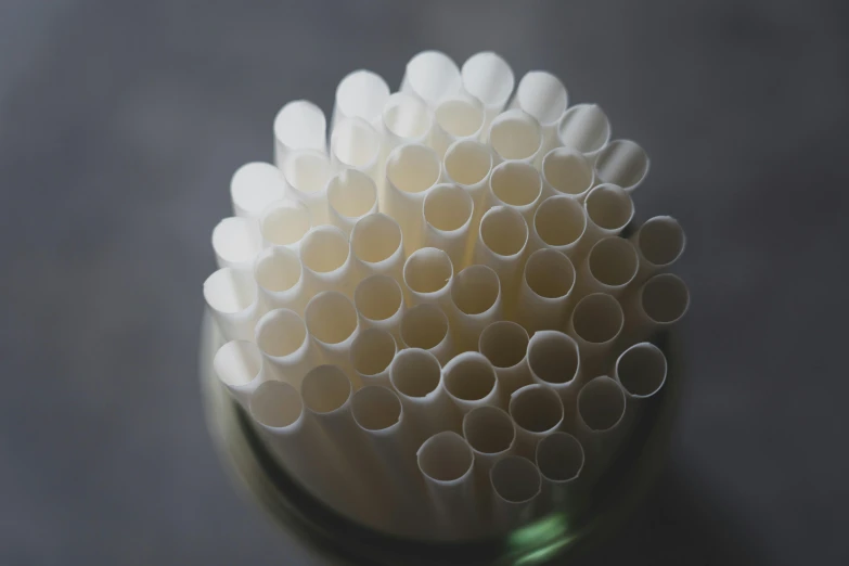 a glass filled with white straws sitting on top of a table