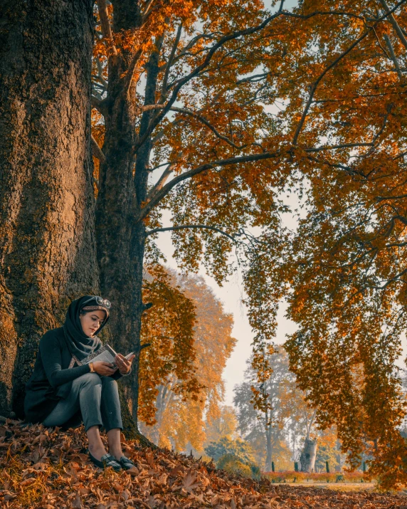 a woman sitting under a tree reading a book, by Sebastian Spreng, pexels contest winner, muted fall colors, snapchat photo, cinematic outfit photo, today\'s featured photograph 4k