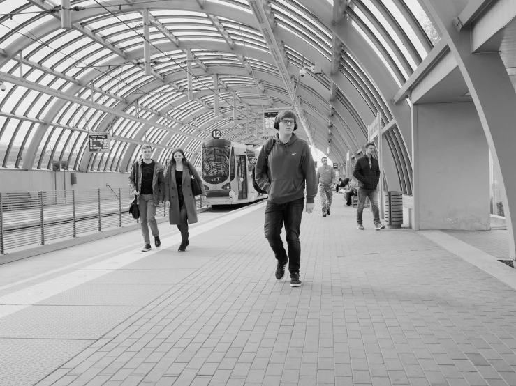 a black and white photo of people at a train station, a black and white photo, by David Palumbo, conceptual art, yeg, walking towards camera, monorail station, tunnel
