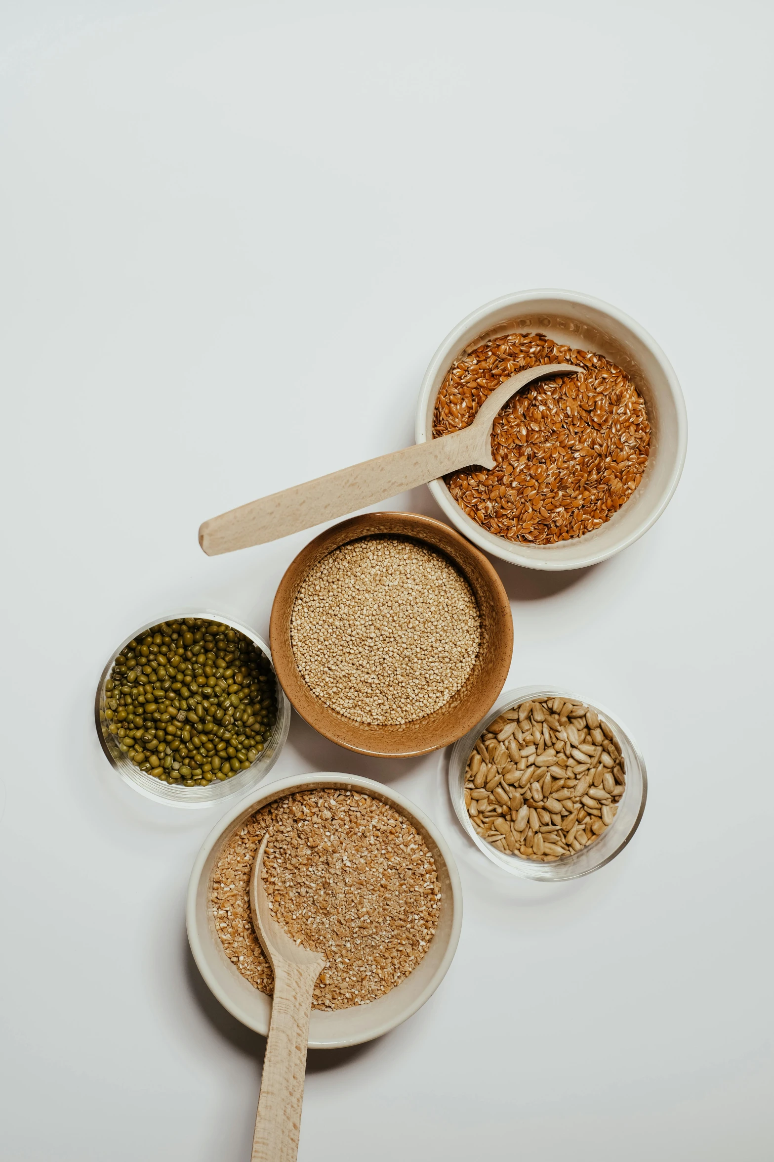 a table topped with bowls filled with different types of cereal, pexels, renaissance, plain background, detailed product image, mineral grains, greens