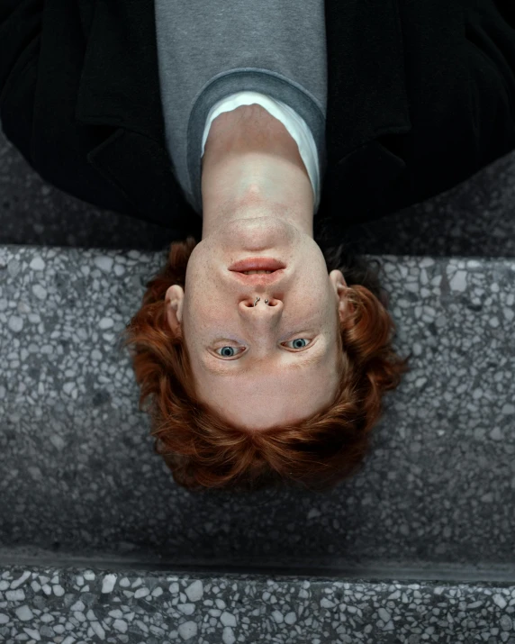 a close up of a person laying on some stairs, by Jan Rustem, trending on unsplash, hyperrealism, ginger hair, very symmetrical face, floating in mid - air, androgynous male
