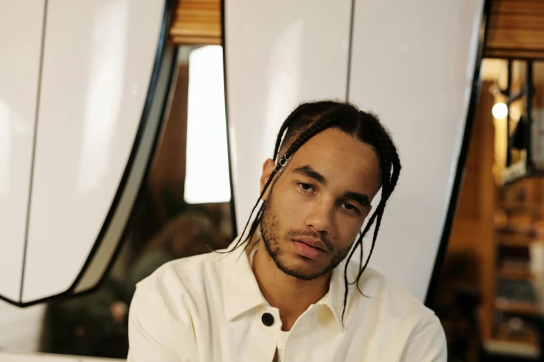 a man with dreadlocks sitting in front of surfboards, an album cover, pexels contest winner, realism, jayson tatum, wearing a white button up shirt, zoë kravitz, portrait shot 8 k