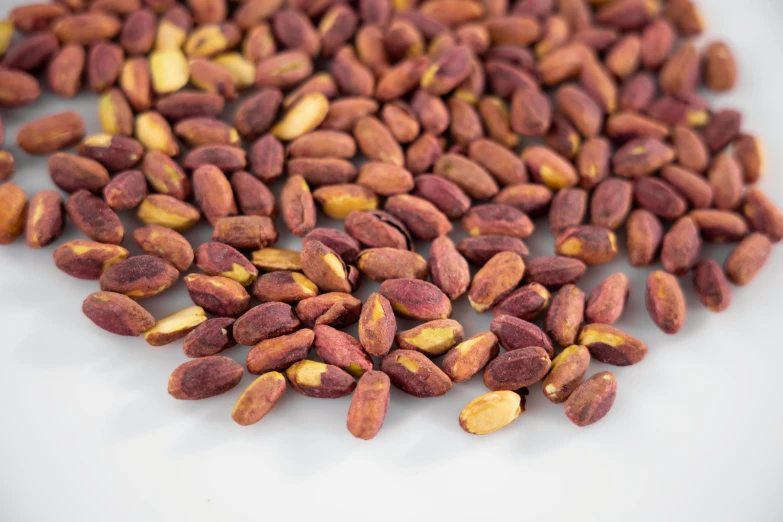 a pile of nuts sitting on top of a white plate, faded red and yelow, detailed product image, peanuts, hexagonal shaped