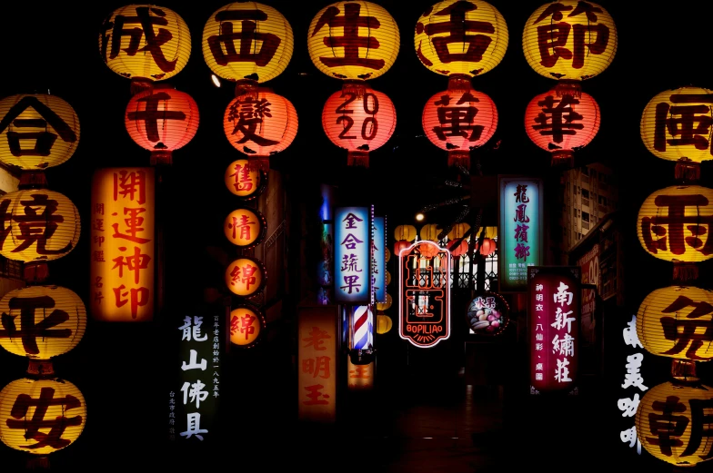 a group of lighted up signs hanging from the side of a building