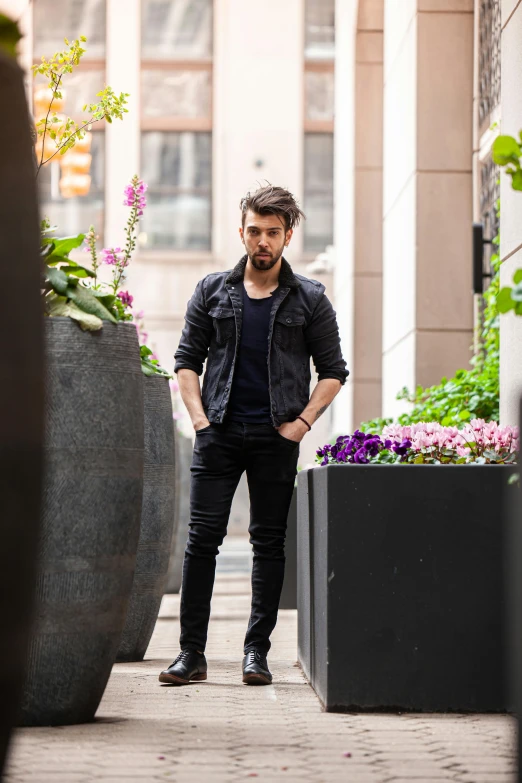 a man standing on the sidewalk next to flowers