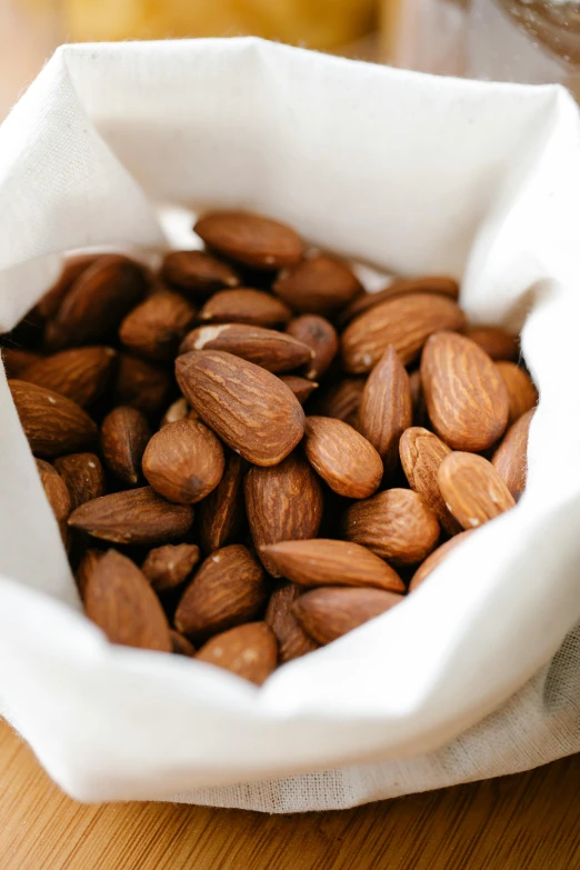 a bowl filled with almonds sitting on top of a wooden table, pouches, zoomed in, product shot, paper