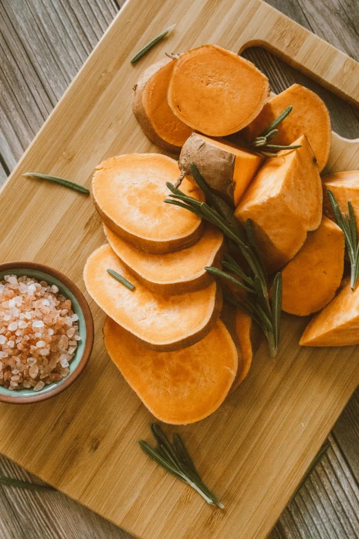 a wooden cutting board topped with sliced sweet potatoes, unsplash, renaissance, square, salt, high quality photo, alternate angle