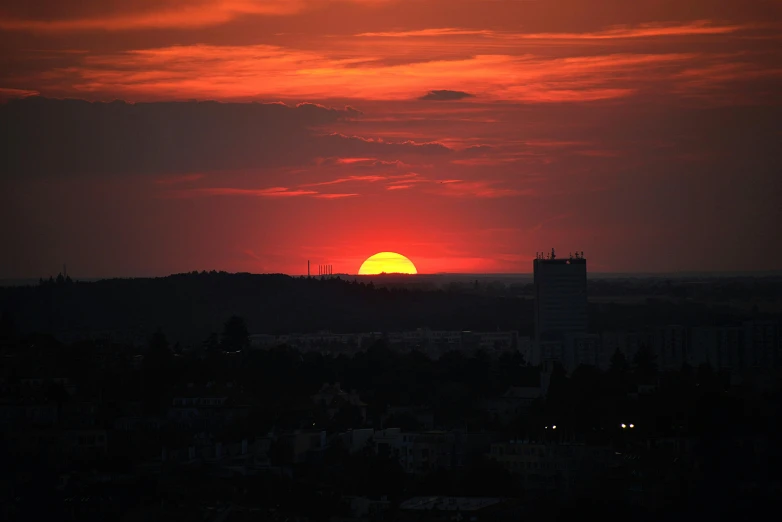 a view of the sun setting over a city, by Attila Meszlenyi, pexels contest winner, big red sun, humid evening, no cropping, video