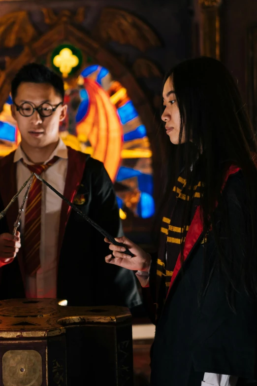 a group of people standing around a table, hogwarts gryffindor common room, lee madgwick & liam wong, standing in a church, he is casting a lighting spell