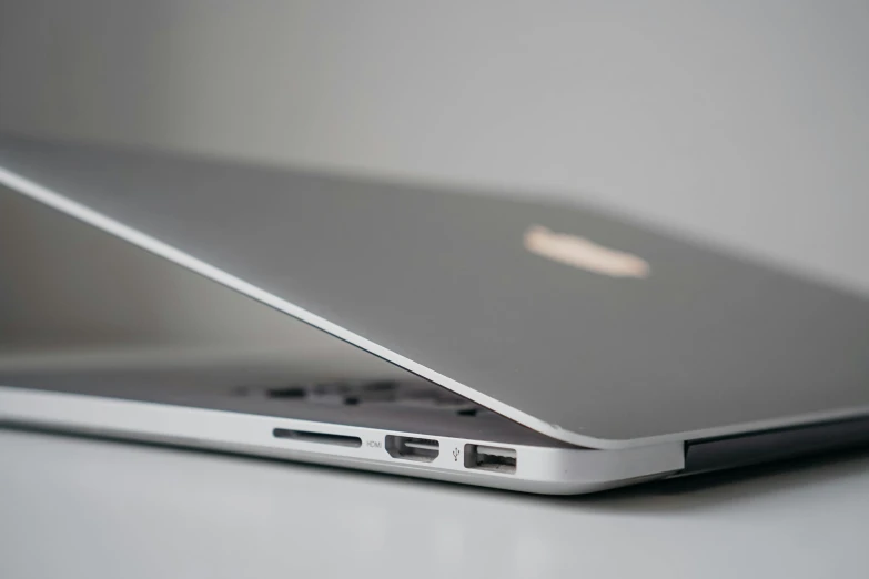 a close up of a laptop computer on a table, by Carey Morris, pexels, on a gray background, three quarter profile, apple, sleek spines