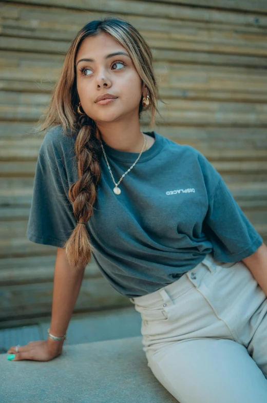 a woman sitting on a ledge wearing a t - shirt and jeans, a portrait, by Carey Morris, trending on pexels, portrait sophie mudd, in white lettering, ((greenish blue tones)), detail shot