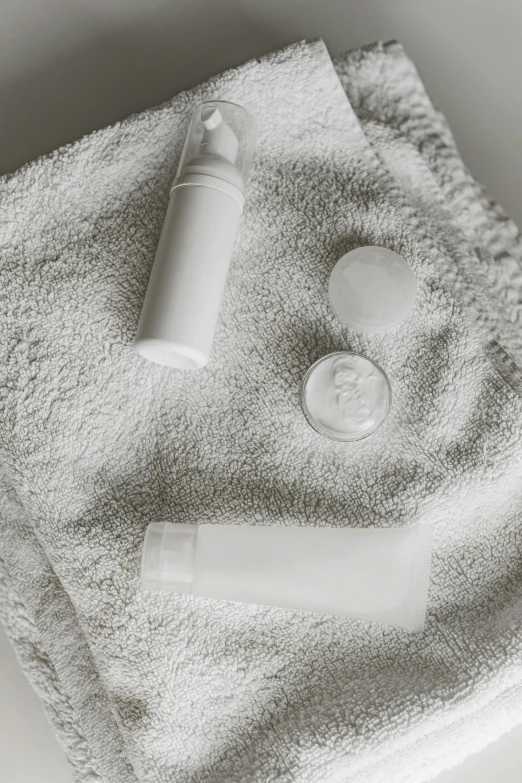 a bottle of lotion sitting on top of a towel, by Adam Marczyński, pexels contest winner, plasticien, buttons, all white, while marble, high samples