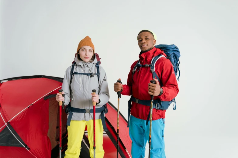 a man and a woman standing next to a tent, trending on pexels, figuration libre, red sport clothing, technical suit, avatar image, mix of ethnicities and genders