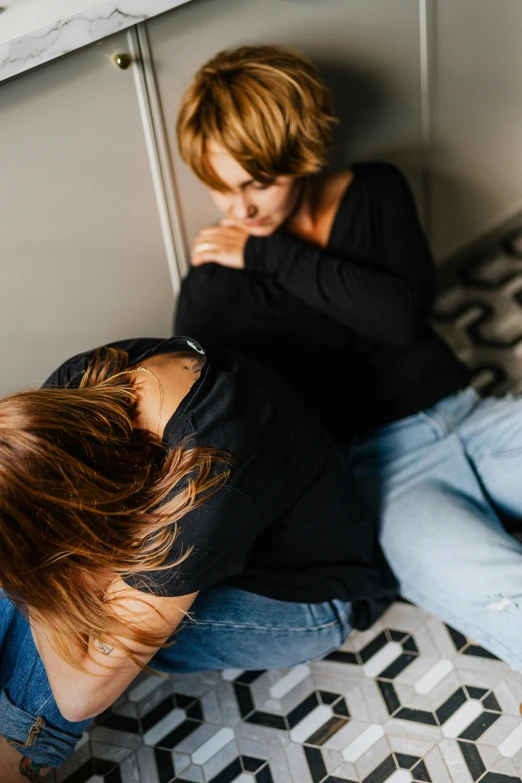 a woman sitting on the floor with her head down