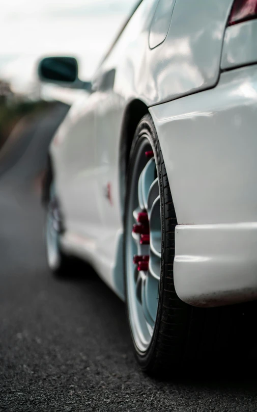 the back end of a white car on a city street