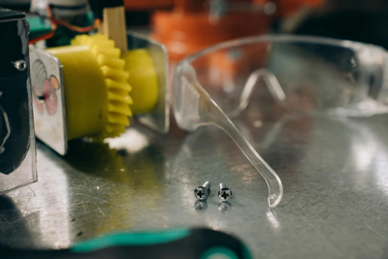 a pair of glasses sitting on top of a table, screws and bolts, tiny robots, a close up shot, creating a soft