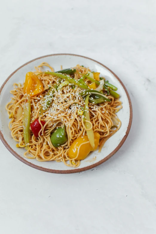 a white plate topped with noodles and veggies, vibrant color with gold speckles, 7