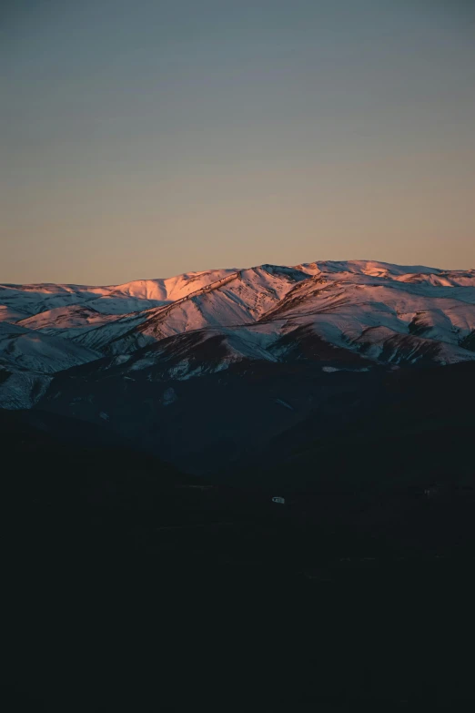 snowy mountain range with sunset light on top of it