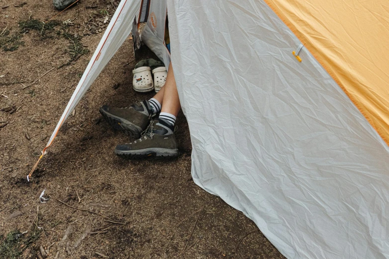 a person that is sitting inside of a tent, by Jessie Algie, pexels contest winner, white shorts and hiking boots, hidden message, cramped, low detail