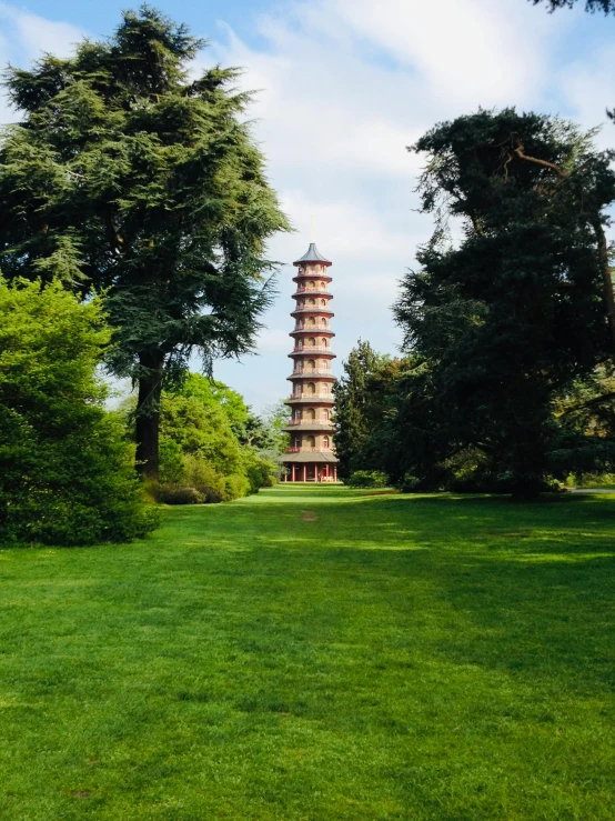 a small tower stands behind some trees in the grass