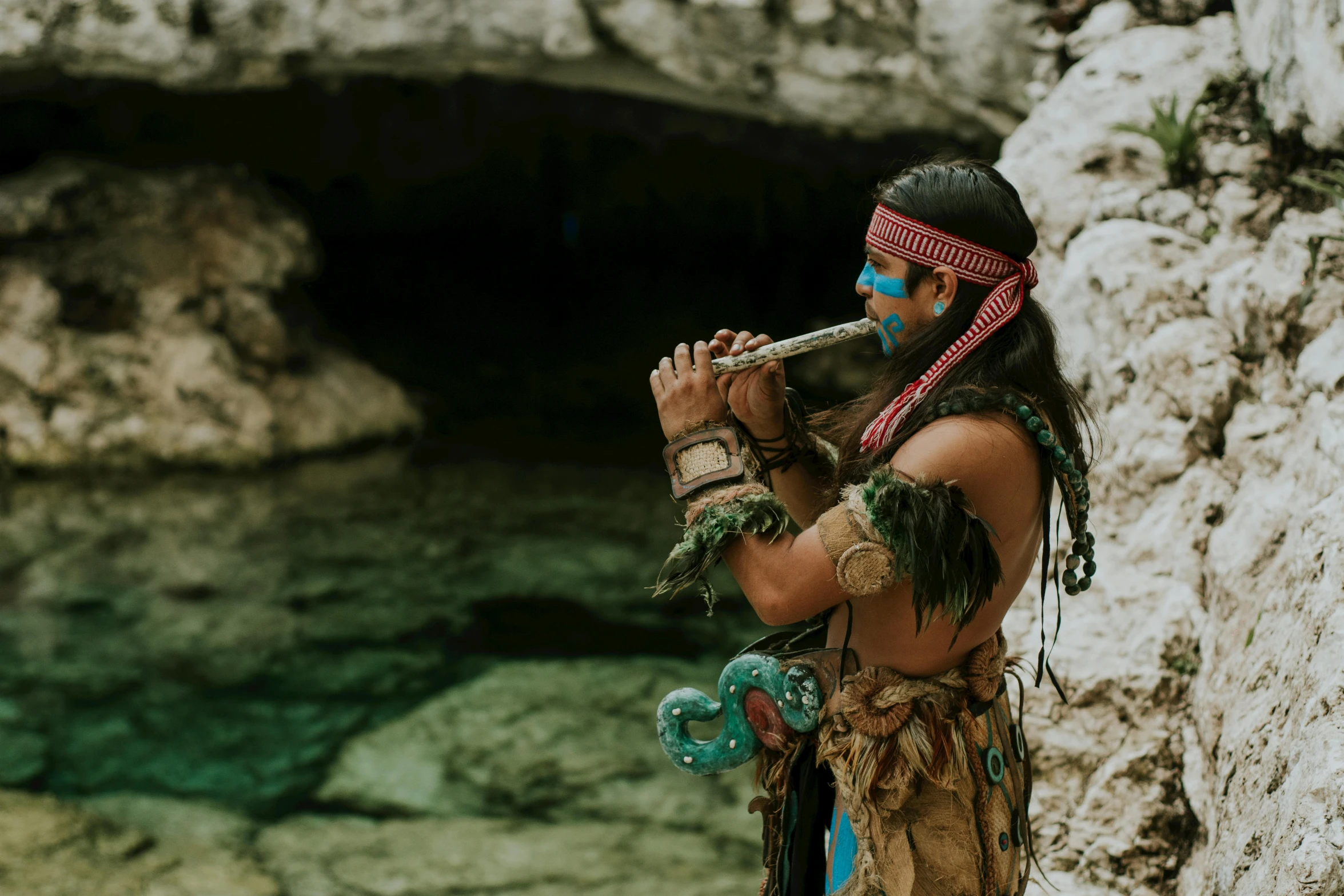 a man playing a flute in front of a cave, pexels contest winner, danza azteca dancers, turquoise jewelry, pirate clothing, avatar image