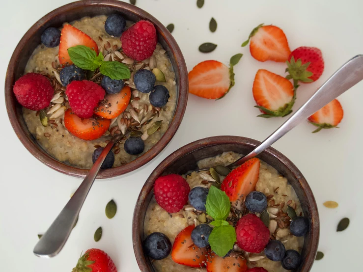 two bowls of oatmeal with strawberries and blueberries, a portrait, by Emma Andijewska, pexels, renaissance, multicoloured, greens), foil, manuka