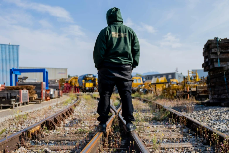 a man in a green hoodie standing on a train track, yard, profile image, teddy fresh, rail tracks lead from the mine