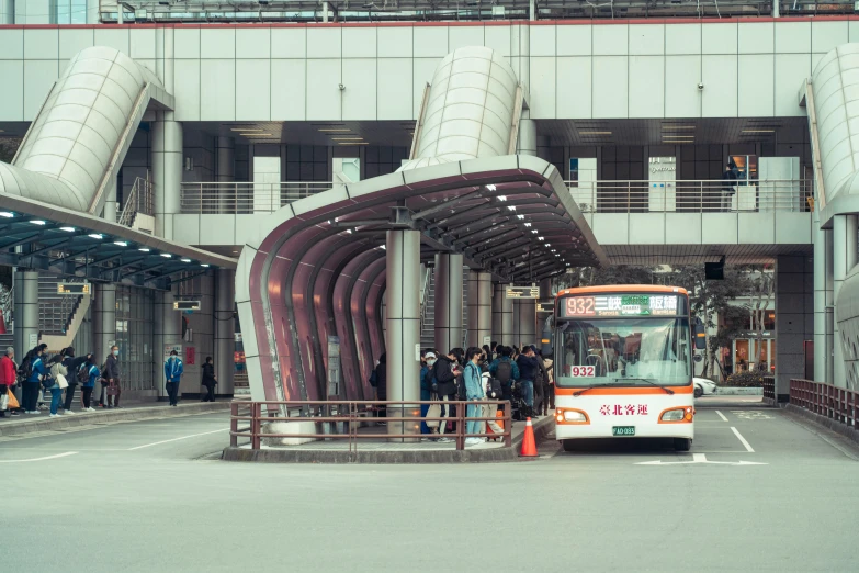 an orange and white bus on street next to tall building