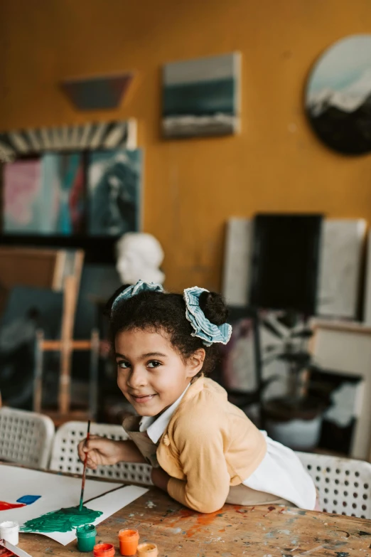 a little girl that is sitting at a table, pexels contest winner, visual art, wearing hair bow, smiling confidently, in the gallery, on a yellow canva
