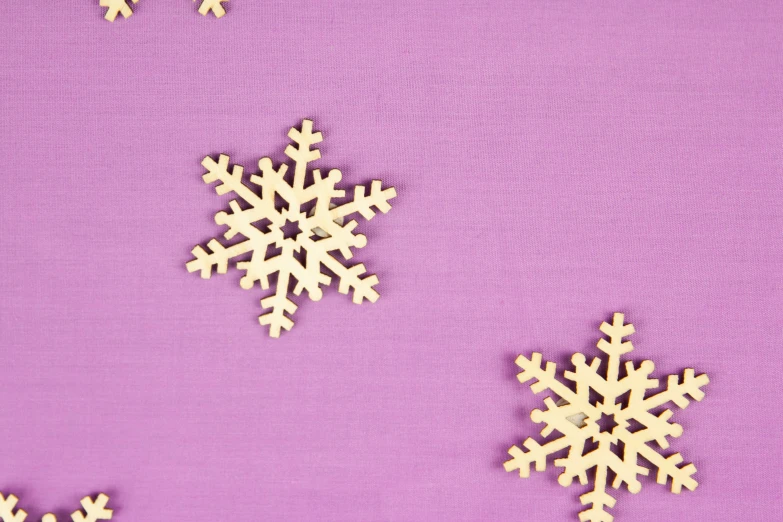 two snowflakes cut out on a purple surface