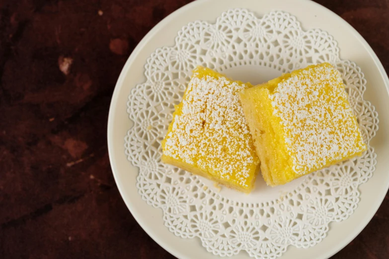 a white plate topped with two pieces of lemon bars, inspired by Géza Dósa, hurufiyya, 10 mm, thumbnail, charming, fan favorite