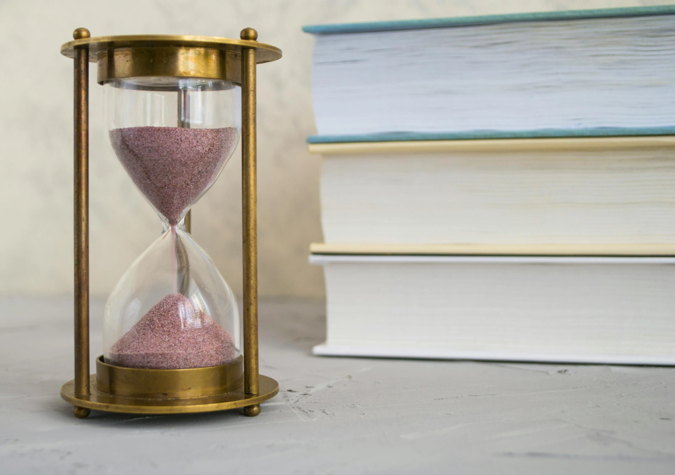 a hourglass sitting next to a stack of books, pexels contest winner, freeze time, gold, school curriculum expert, still photograph